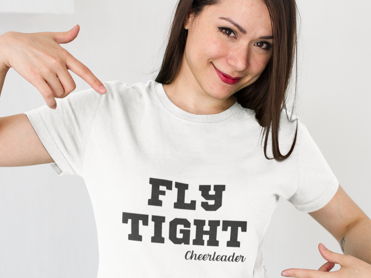 Cheerleader pointing to a t-shirt that says flight tight cheerleader