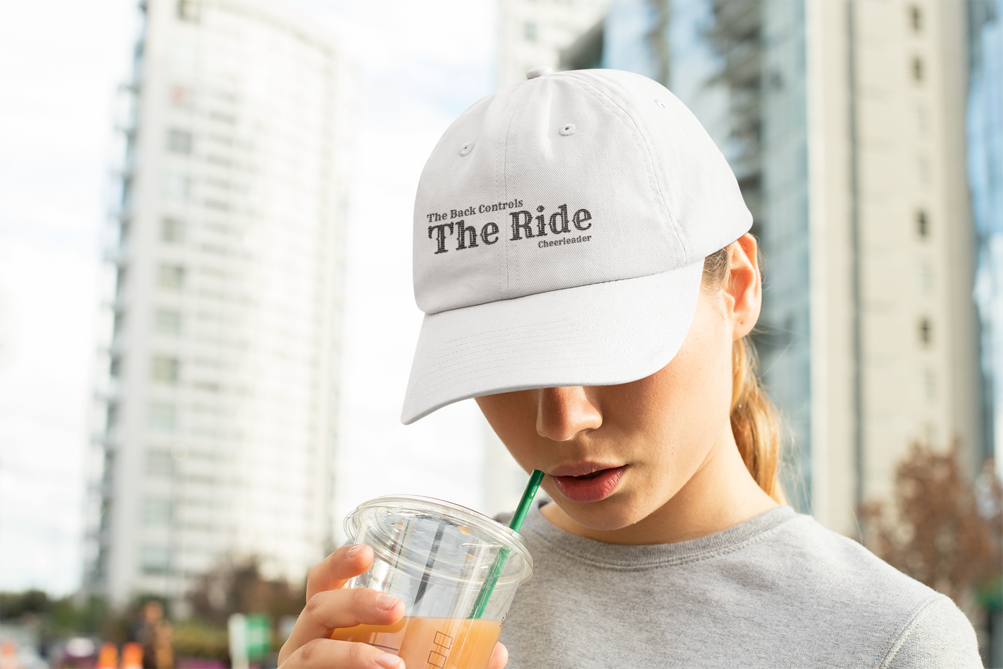 Cheerleader in the city drinking a Starbucks and wearing a back controls the ride hat